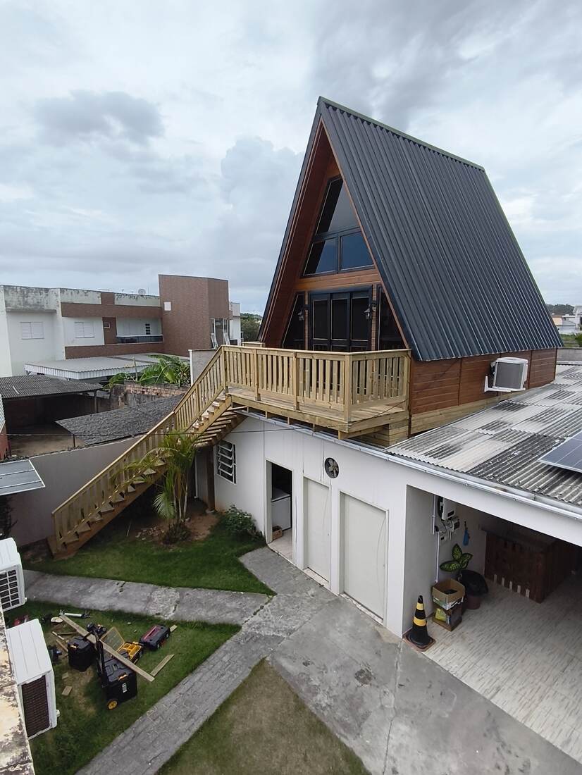 Chalé estilo A-frame com telhado metálico preto e deck elevado