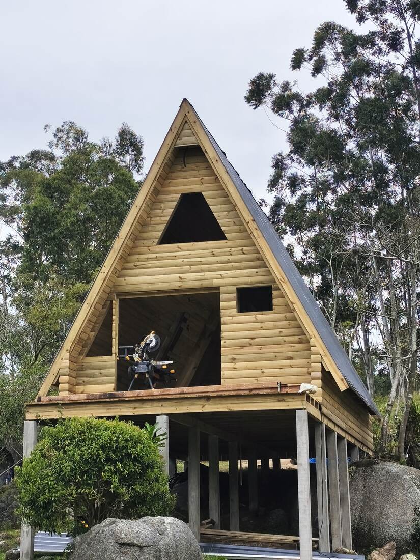 Chalé A-frame finalizado com telhado escuro entre árvores