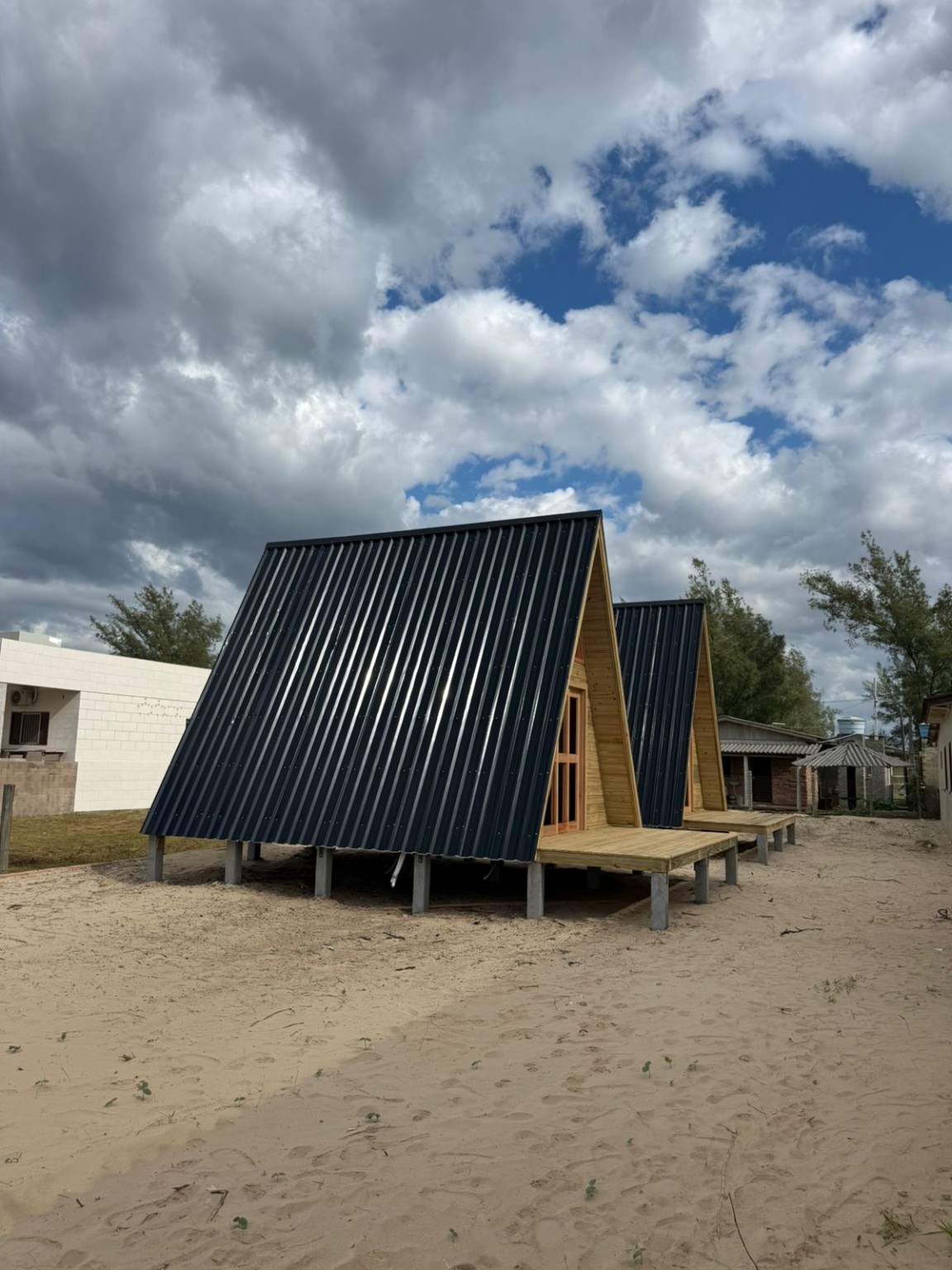 Dois chalés de madeira em formato A-frame com cobertura escura em Tubarão