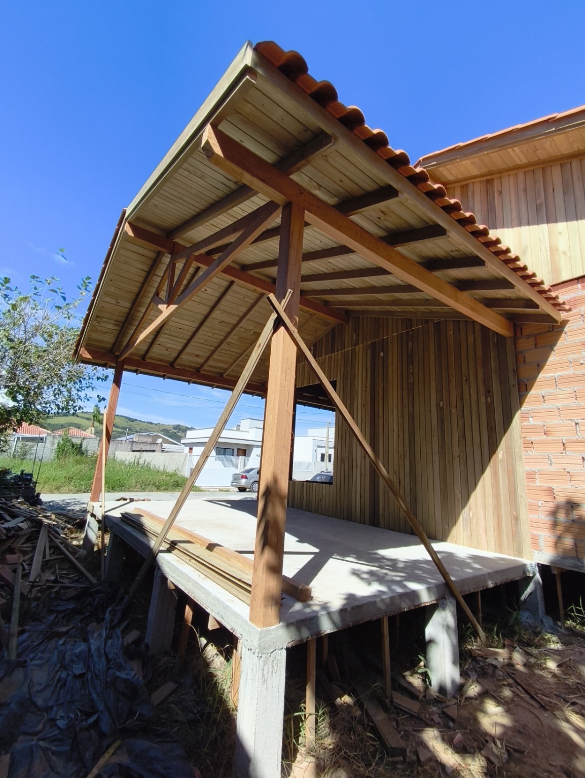 Cobertura de varanda com estrutura e forro de madeira e telhas cerâmicas em Tubarão