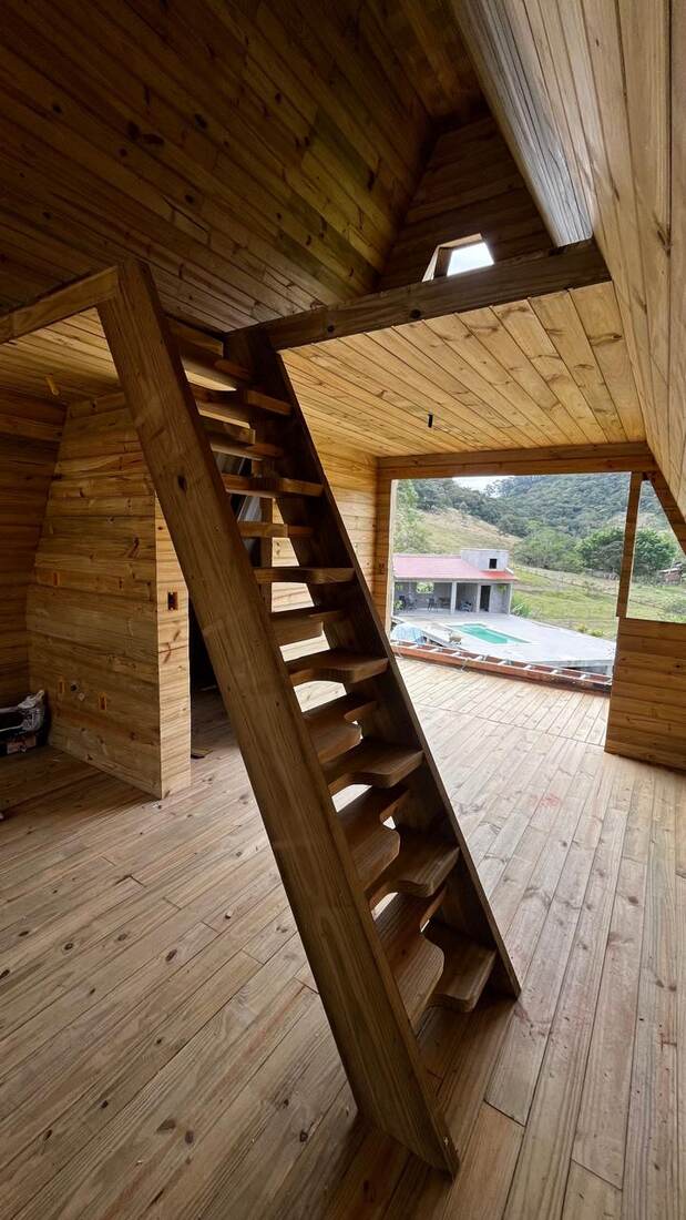 Interior em madeira com escada e vista para área de piscina